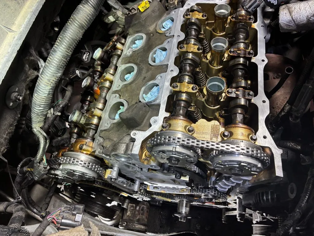 Engine mid-repair with the valve cover off, camshafts and a fresh timing chain exposed