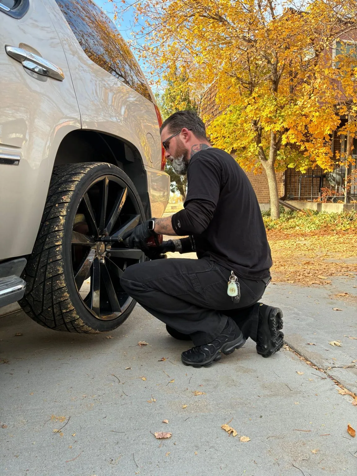Jeff crouched at the wheel of an SUV in a customer driveway, zipping lug nuts off with an impact wrench